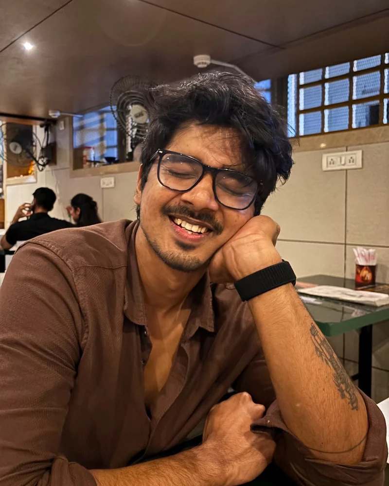 Sathyasiddha Pattanaik, smiling, leaning on one hand at a café table.